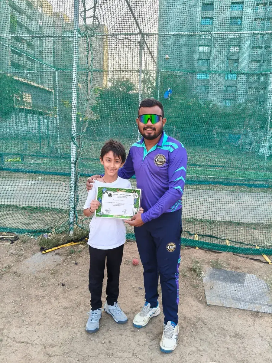Coach Kevin Kanojiya presenting a Desire Cricket Academy certificate to an international student after a personal training session in Ahmedabad